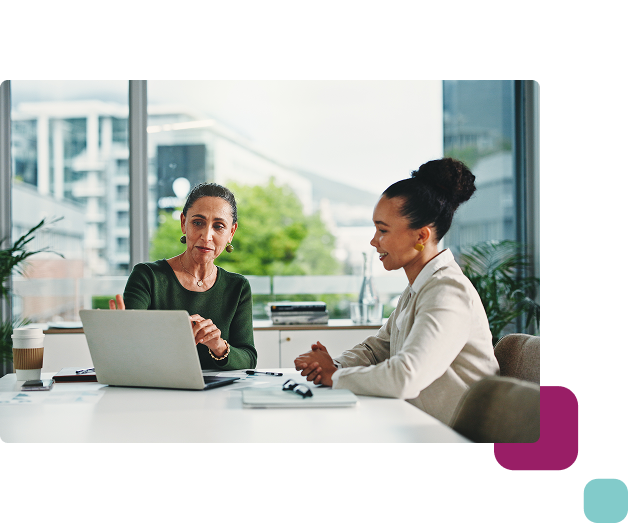Two professionals sitting at a desk in a modern office discussing training